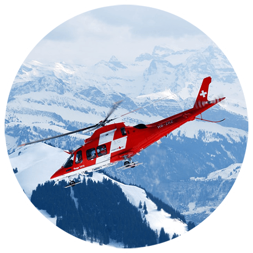 Rega Helikopter in der Luft vor den Alpen