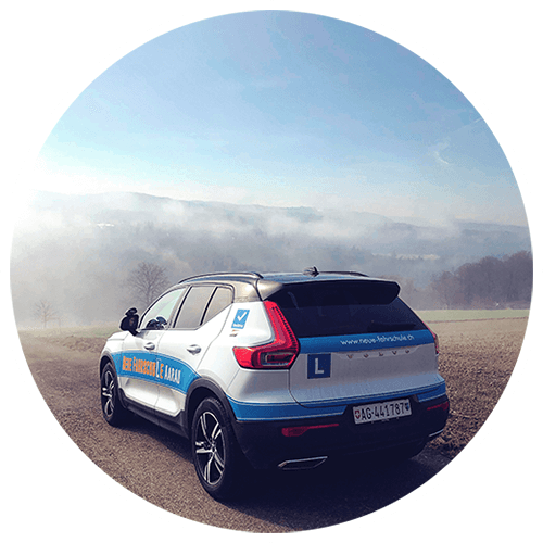 Fahrschulauto Vovlo der Neue Fahrschule von hinten mit blauem L und Blick auf Nebel