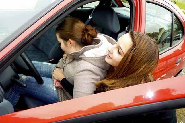 Frau holt andere Frau mit Rettungsgriff aus rotem Auto
